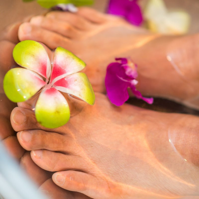 zwei gepflegte Füße im Wasser mit bunten Blüten