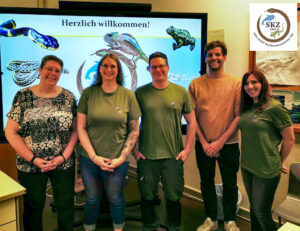 das Prüfungsteam Terraristik und die Schulungsteilnehmer stehen vor einem Smartboard